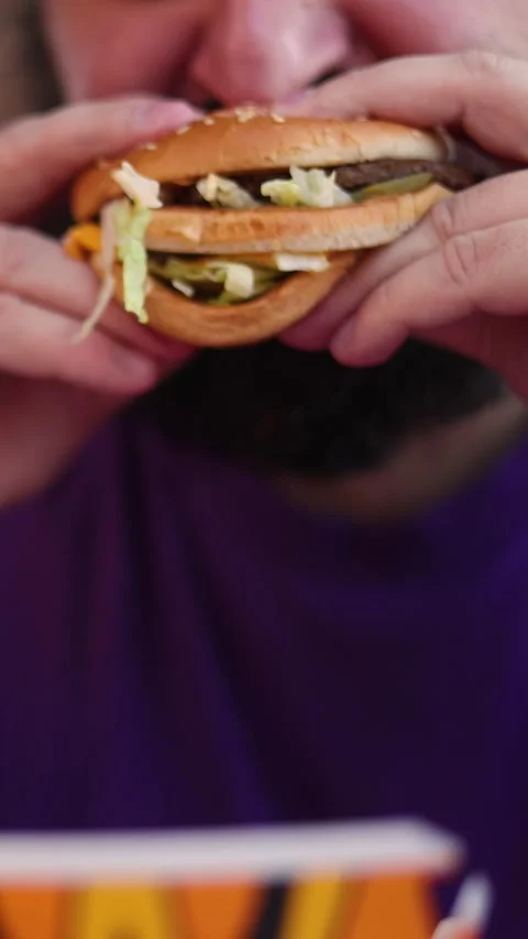 Vertical defocused video. Unknown fat man with beard eats Big Mac burger Stock Footage 339038887