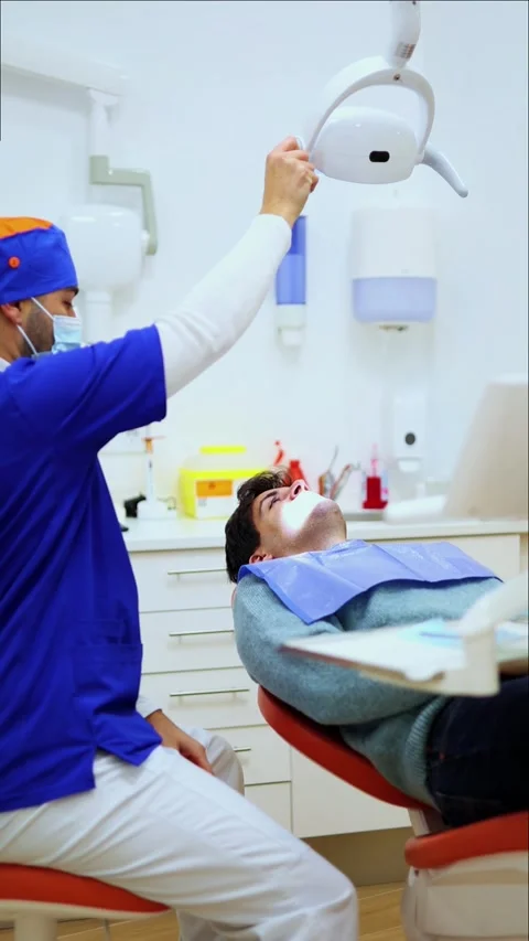 Vertical Dentist adjusting dental light and looking at x-ray Stock Footage 295784559