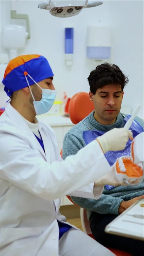 Vertical Dentist explaining treatment using teeth model Stock Footage 295784602