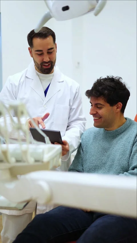 Vertical Dentist showing information on tablet to patient Stock Footage 295784560