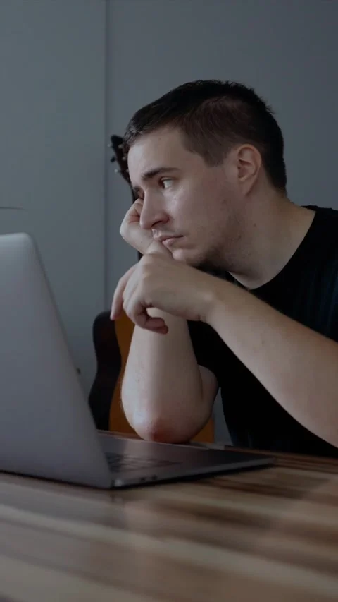 Vertical of Depressed man tries hard to continue work on laptop at home Stock Footage 274154464