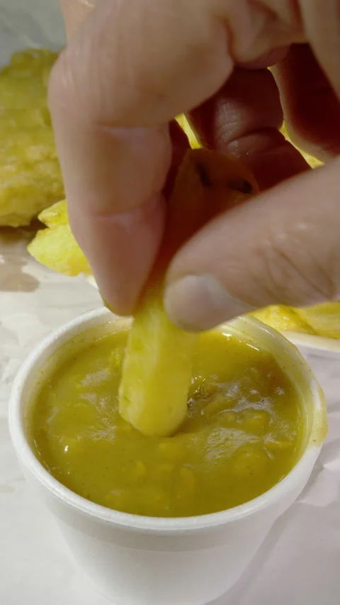 Vertical - Dipping a chip into a pot of curry sauce in front of fish and chips. Stock Footage 280228095
