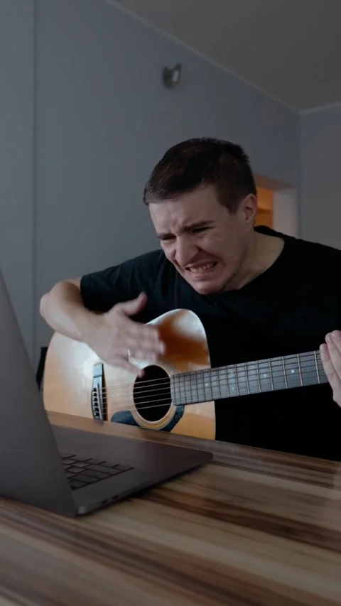 Vertical of Disappointed man fails playing guitar watching tutorial 動画素材 274153375