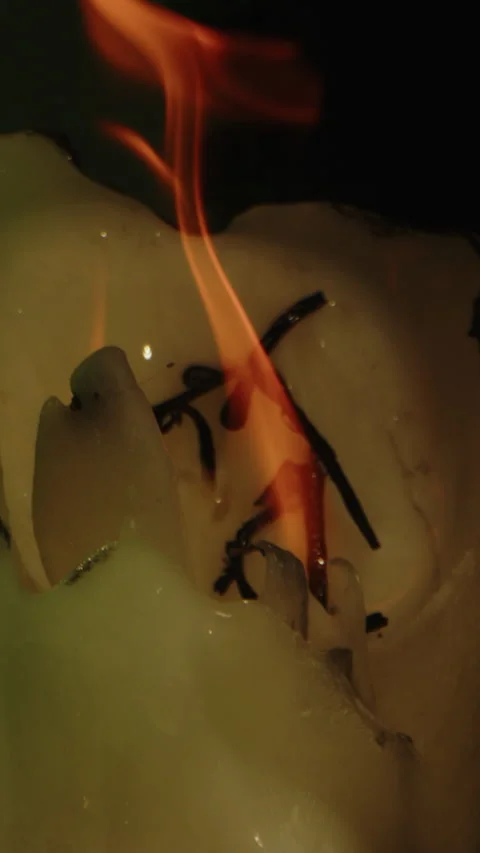 Vertical dolly out of a candle burning intensely on an occult altar in a dark Video stock 336374138