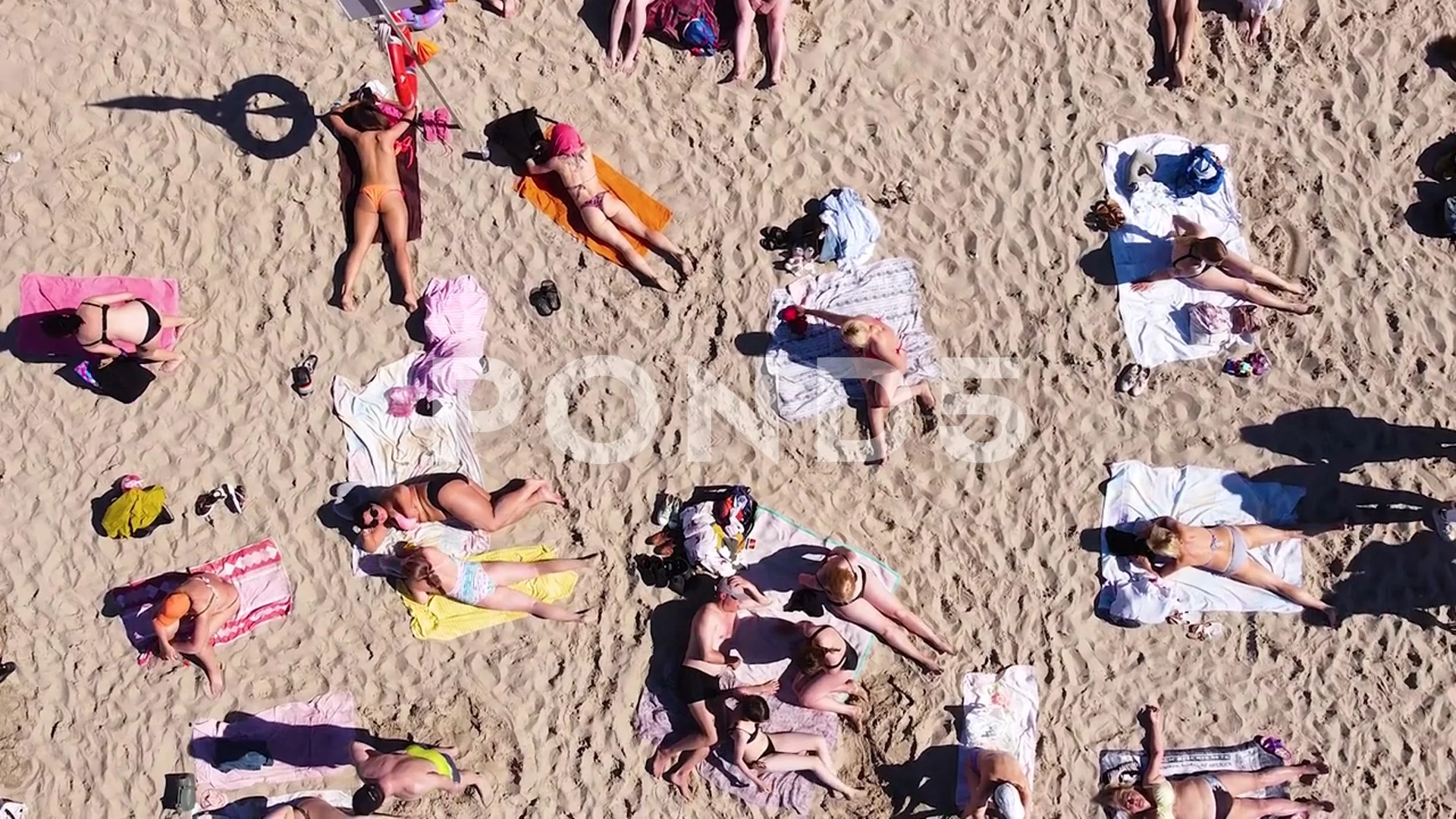 a vertical downward view from a drone of people relaxing on the beach