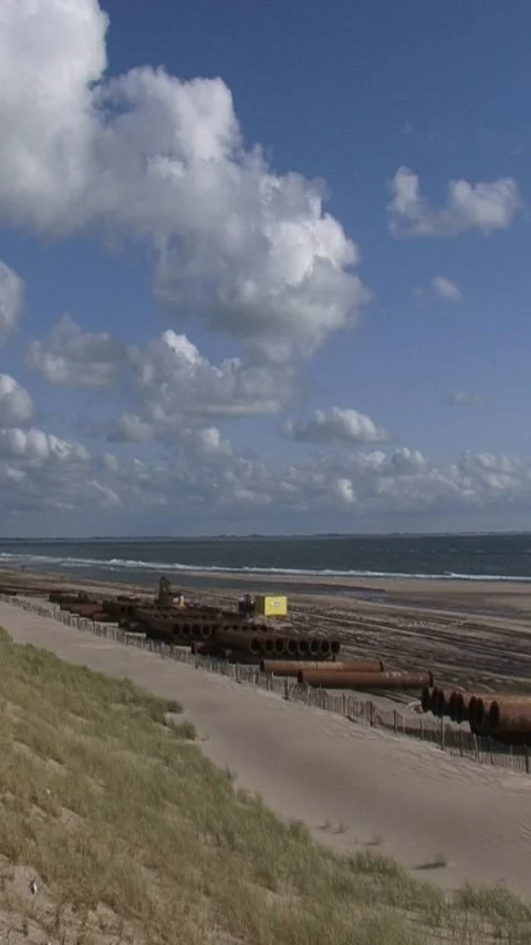 Vertical - Dredging pipes against artificial dune with planted marram grass Video stock 313880862