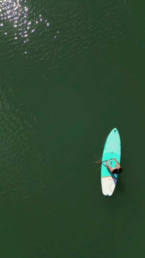 Vertical Drone aerial overhead closeup hispanic girl Paddle Surfing in the .. Stock Footage 271100658