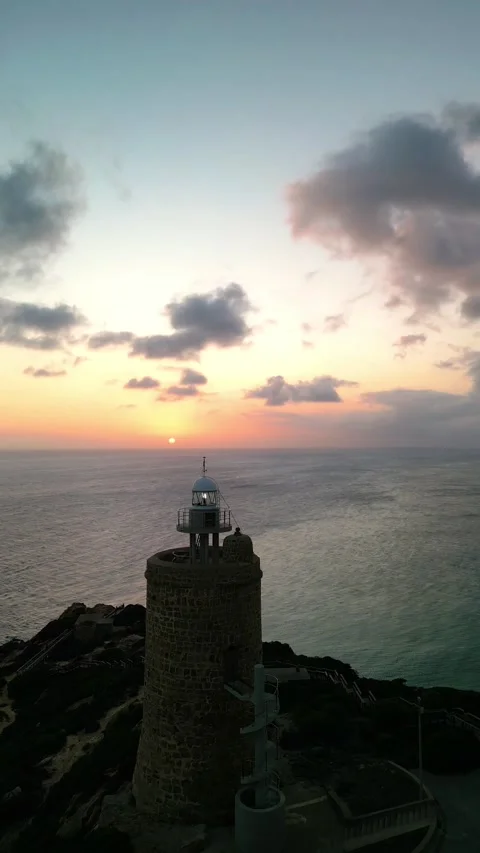 Vertical drone Aerial view of lighthouse on sea cliffs during sunset Stock Footage 293064152
