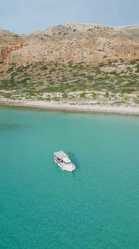 Vertical drone aerial view of small pleasure boat anchored in crystal clear.. Stock Photos