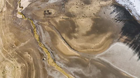 Vertical drone ascent over dry lakebed with abstract textures and stream Stock Footage 332045866