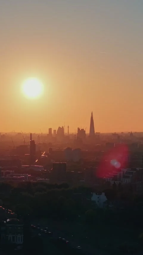 Vertical drone ascent over golden-lit city skyline during warm sunset Stock Footage 309769651