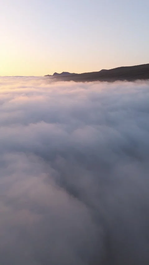 Vertical Drone Flight Above Clouds with Mountain Peaks at Sunset – 4K Relaxing Stock Footage 314600658