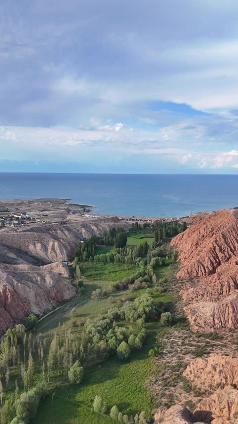 Vertical drone flight over green valley and red mountains in Kyrgyzstan. Stock Footage 315435787