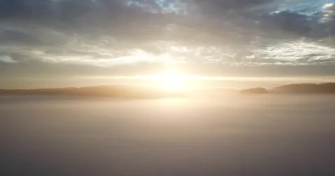 Vertical drone flight through a blanket of fog with a view of a sunrise Stock Footage 293593123