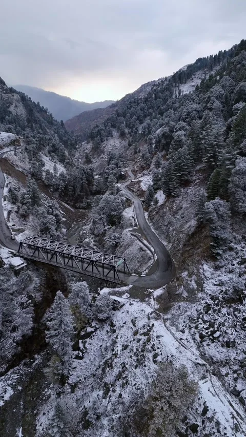 Vertical drone footage of a biker making their way across a scenic, frozen Stock Footage 311151465