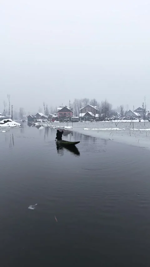 Vertical drone footage of boats creating ripples in Dal Lake during snowfall. Stock Footage 311021580