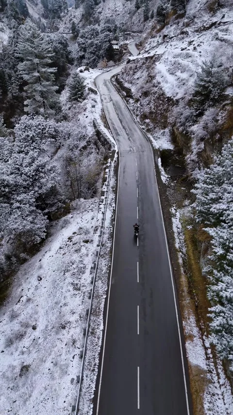 Vertical drone footage capturing the adventurous spirit of a lone biker on the Stock Footage 311151170