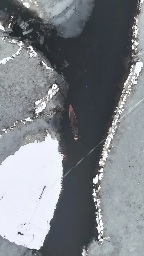 Vertical drone footage capturing boats navigating Dal Lake during snowfall. Stock Footage 311021397
