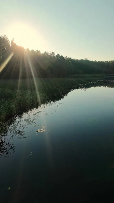Vertical drone footage capturing the serene lake with reflections and a sunlit Video stock 288087319