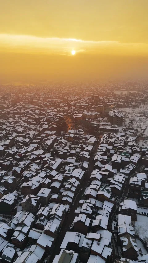 Vertical drone footage of magical winter sunset scenes over snowy rooftops. Stock Footage 311021757
