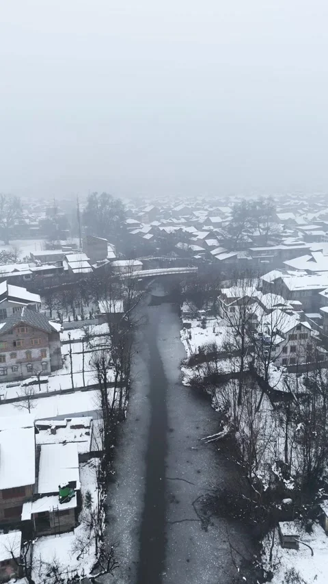 Vertical drone footage showcasing the delicate winter balance of rooftops and Stock Footage 311021369