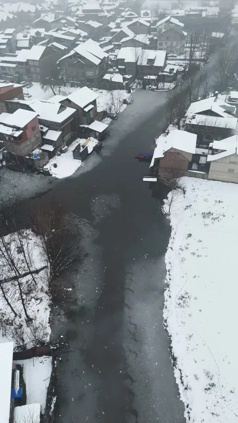 Vertical drone footage of snow-blanketed Srinagar neighborhoods featuring quiet 動画素材 311021385