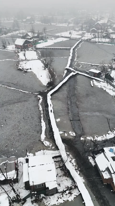 Vertical drone footage of snow-covered wooden bridges adding charm to Dal Lake’s Stock Footage 311021154