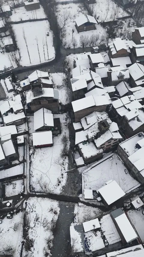 Vertical drone footage of snow-covered rooftops with narrow canals weaving Stock Footage 311021184