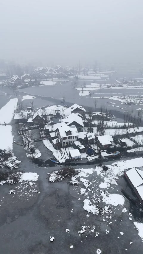 Vertical drone footage of snowfall creating a dreamlike landscape over Dal Lake. Stock Footage 311021671