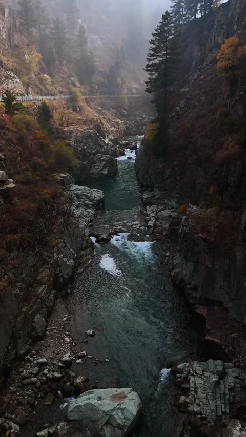 Vertical drone footage of the stream cutting through mountains like nature’s Stock Footage 311152298