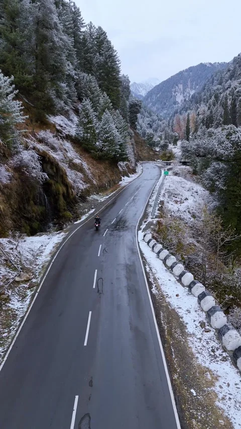 Vertical drone footage tracking a biker as they move through a white wonderland Stock Footage 311151022