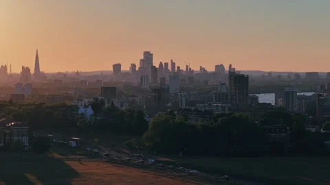 Vertical drone lift over warm-lit modern city skyline during golden sunset Stock Footage 309769359