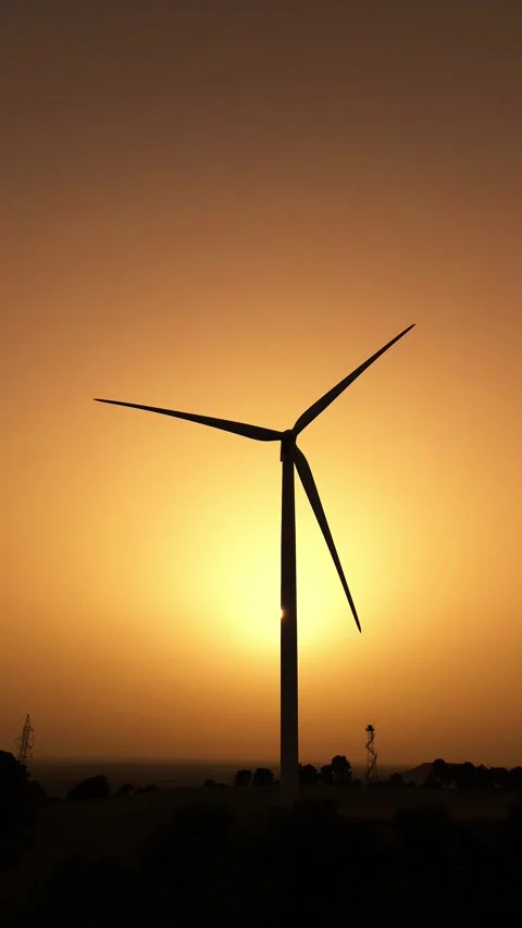 Vertical drone orbit around wind turbine silhouette in orange hazy sunset Stock Footage 331284267