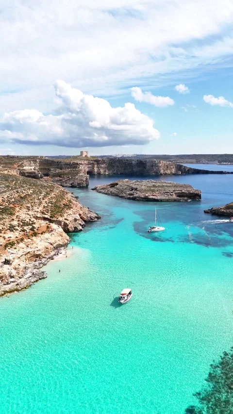 Vertical Drone pullback tracking shuttle boat across Blue Lagoon with Cominotto Stock-Footage 333991169