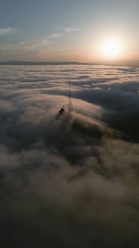 Vertical drone shot approaching a broadcasting transmitter mast in foggy CA Stock Footage 342783580
