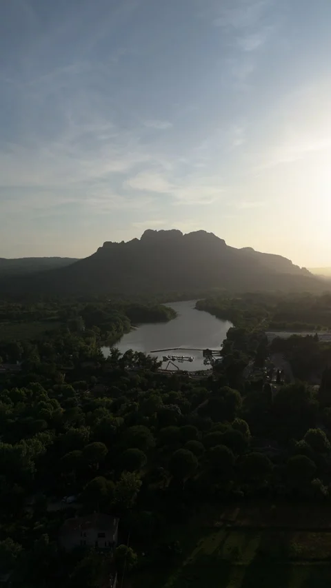 Vertical drone shot approaching Rocher de Roquebrune mountain and river, sunset Видео 336794416
