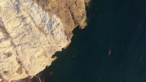 Vertical Drone Shot of Black Beach in Santorini with Kayaker Near the Rocks. Stock-Footage 335017649