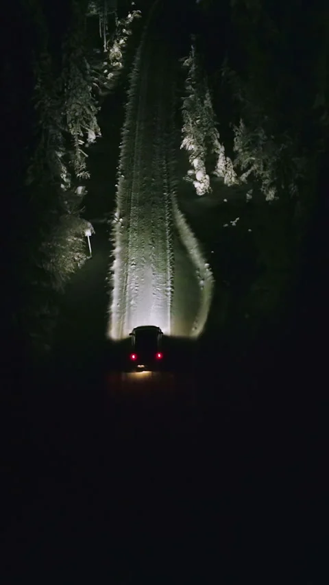 Vertical drone shot of a car driving on a snowy road, winter night in Stock Footage 288991498