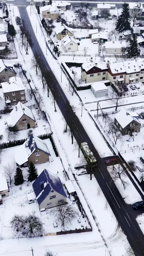 Vertical drone shot of a city bus traveling through a wintry suburb, revealing Stock Footage 328636115