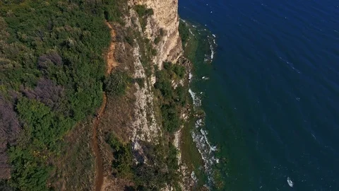 Vertical drone shot of a cliff on Lake Garda and a young blonde girl walks Stock-Footage 129186936