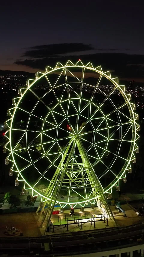 Vertical drone shot orbiting the ferris wheel of Aztlan Park, night in CMDX 動画素材 303472754