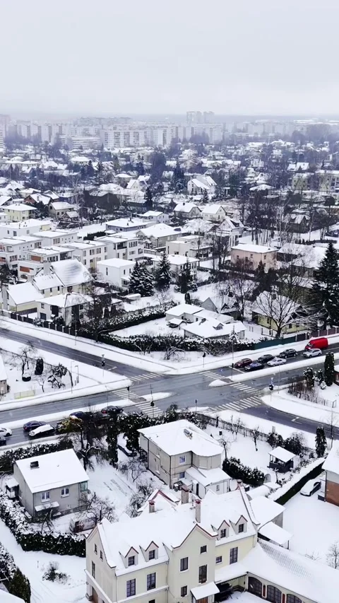 Vertical drone shot over a snow-covered suburb and busy intersection, cars Video stock 327917429