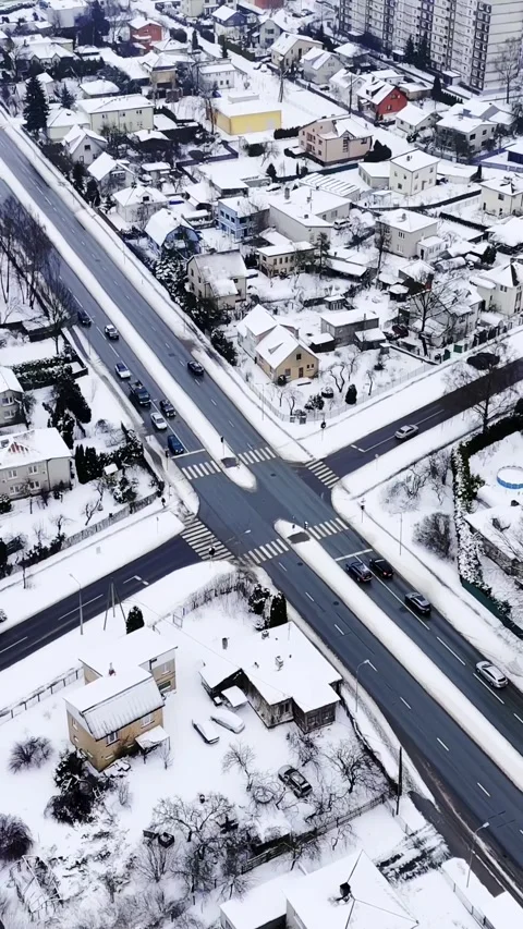 Vertical drone shot over snow-covered suburb junction with zebra crossings and 動画素材 328356035