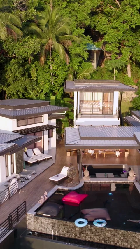Vertical drone shot of people at a pool villa meditating near palm trees on a Stock Footage 319889570