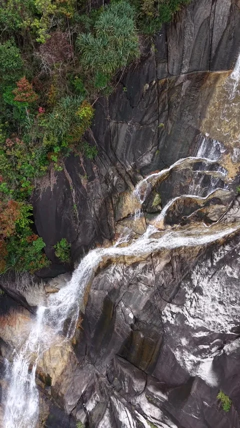 Vertical Drone Shot Pulling Back from Tall Waterfall in Deep Jungle Valley 스톡 동영상 343699636