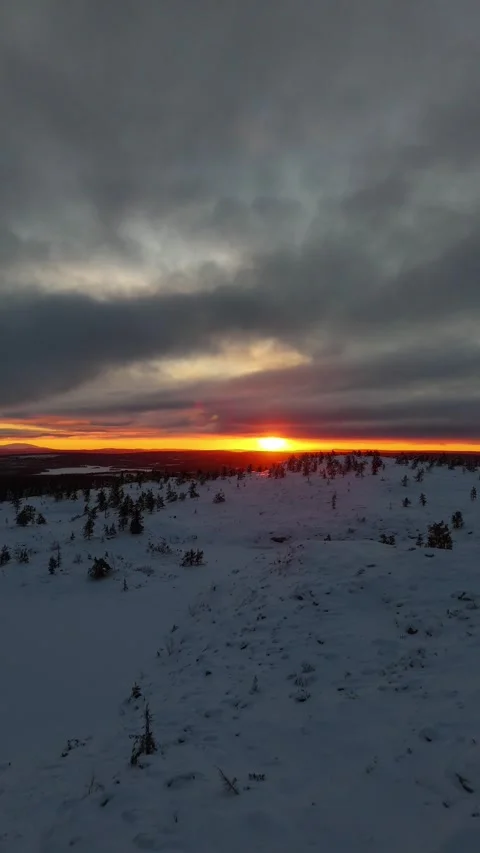 Vertical drone shot revealing winter sunset behind snowy mountain top in Lapland Stock Footage 301344801