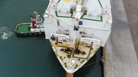 Vertical drone shot of ship being pushed into position at busy port. Stock Footage 87851456