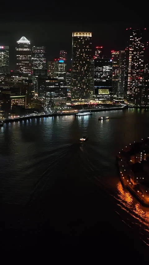Vertical drone shot tilting toward illuminated Canary Wharf, night in London Stock Footage 331294533