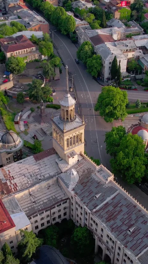 Vertical drone shot tracking and orbiting old cathedral in a city at sunrise Stock Footage 293492987