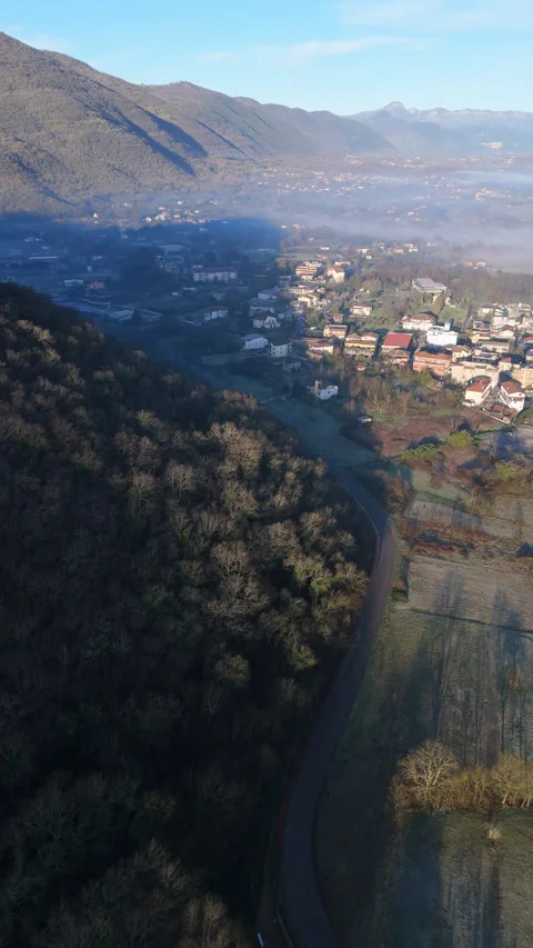 Vertical drone shot of a winding road through a misty Italian valley Stock Footage 328124622